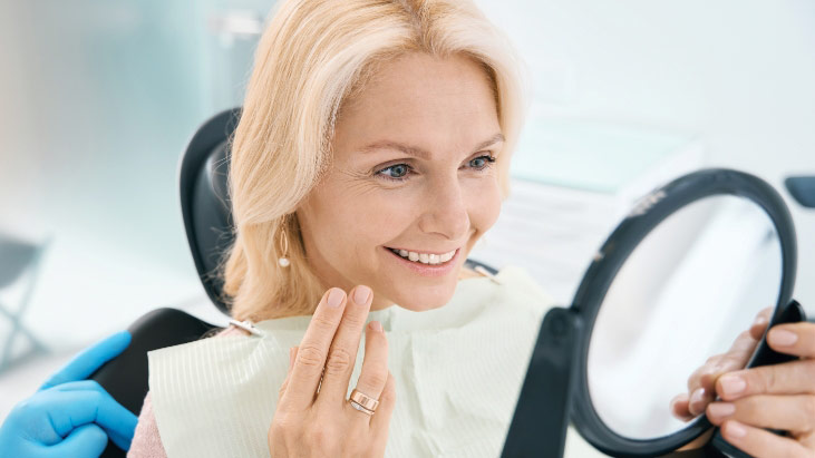 Female Patient Sitting On Dental Chair Showing Thumb And Smiling