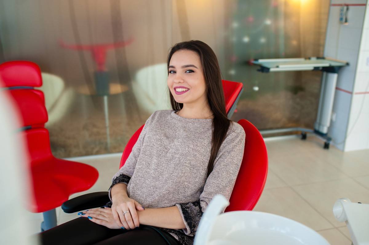 Smiling woman sitting in a dental chair during a cosmetic dentistry consultation for veneers or crowns