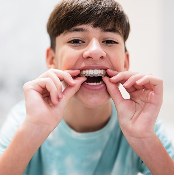 Smiling child with braces practicing oral care to help prevent dental emergencies