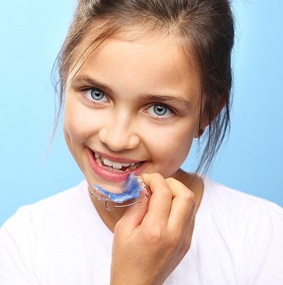 Child holding a removable dental appliance needing emergency dental care